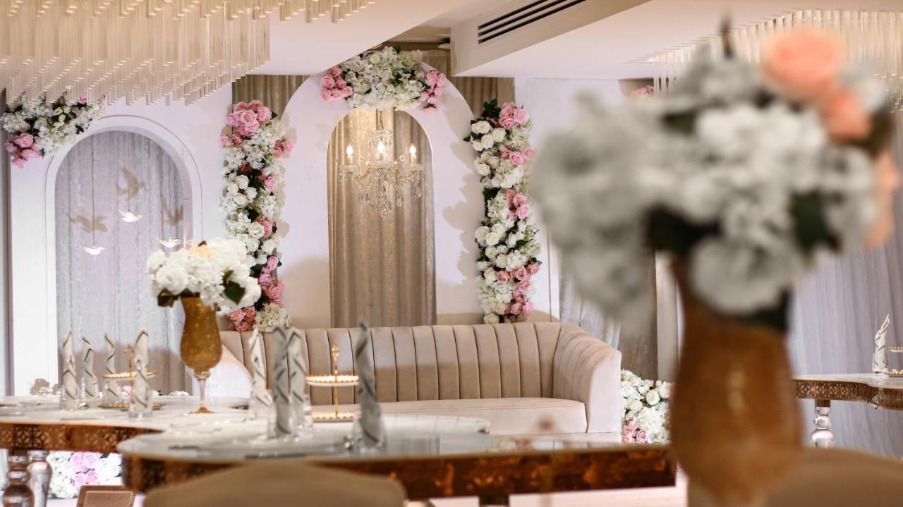 Hotel Millennium Plaza Doha Exterior foto The photo shows an elegantly designed interior space, likely for an event or celebration. In the center, there is a plush sofa with a light-colored upholstery, placed in front of an arch adorned with floral decorations in shades of pink and white. Th