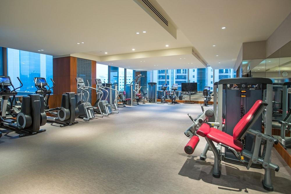 Hotel Millennium Plaza Doha Exterior foto The photo shows a modern gym or fitness center. It features various exercise equipment, including cardio machines like treadmills and stationary bikes, along with strength training machines. The space is well-lit with large windows providing natural 