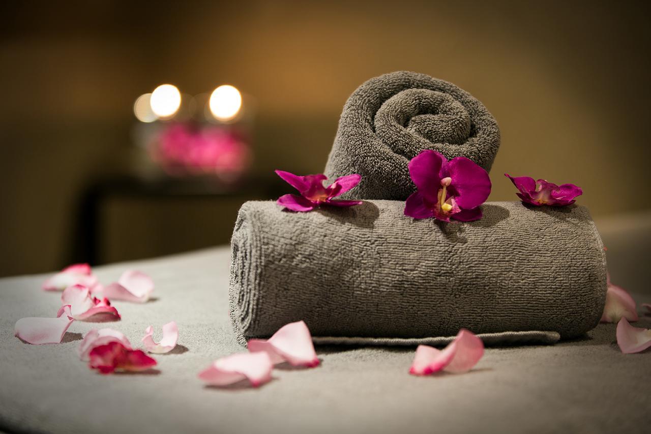 Hotel Millennium Plaza Doha Exterior foto The photo features two rolled gray towels, arranged neatly on a surface. Delicate purple orchid petals are scattered around the towels, enhancing the aesthetic appeal. In the background, there are softly glowing candles, creating a relaxing and seren